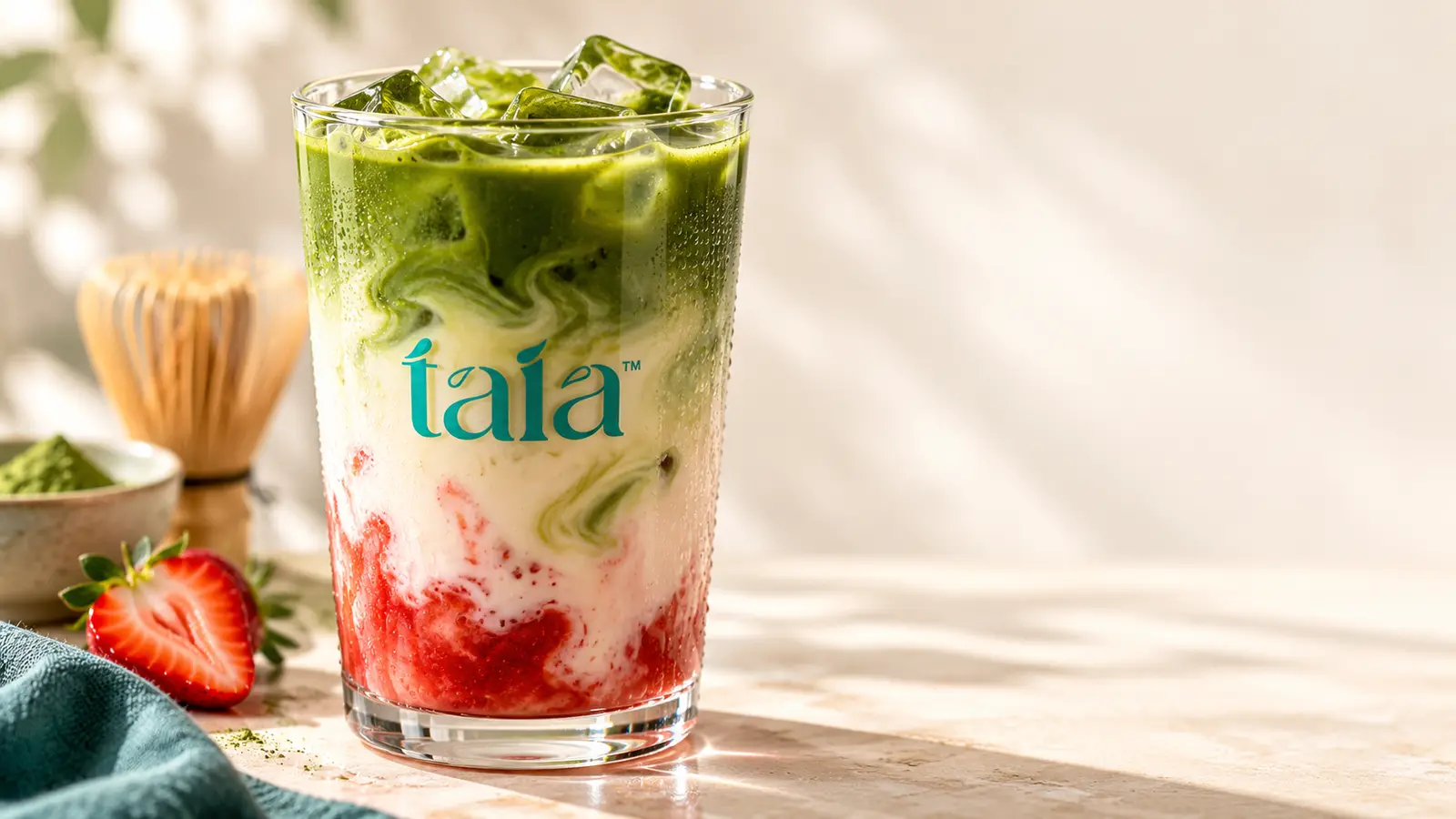 Layered strawberry and matcha drink in a taia glass